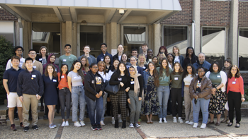 A group of students wearing name-tags stand and smile